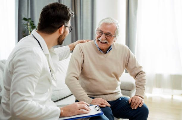 Young doctor and senior man having a conversation sitting on a sofa