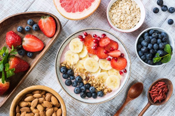 Smoothie bowl with banana slices, strawberry, blueberries, granola and pomegranate seeds. Top view. Healthy lifestyle, healthy eating, dieting, weight loss concept